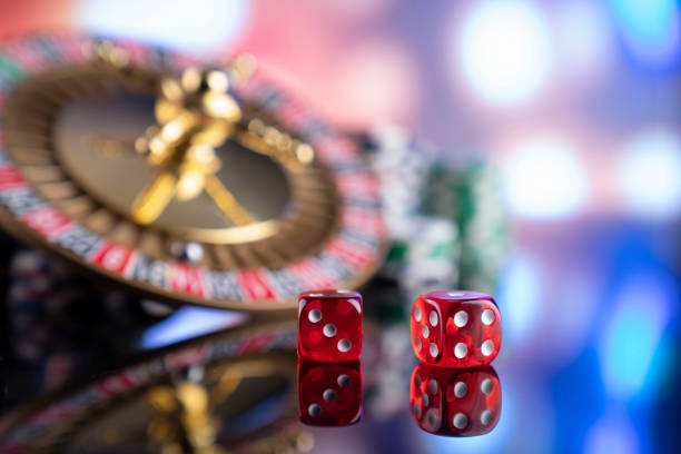 Roulette, dices, cards and poker chips on a colorful bokeh background.